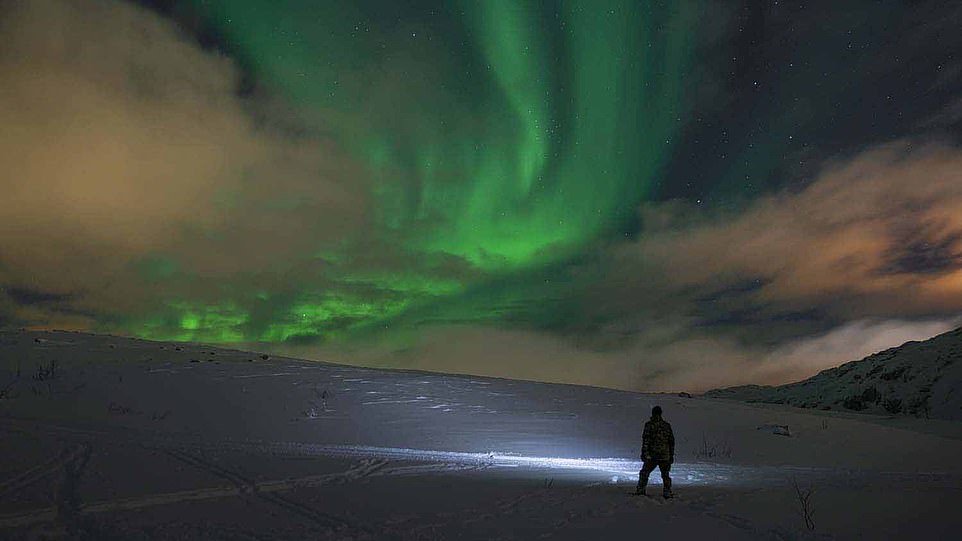 Royal Marine in an Arctic environment under the aurora borealis